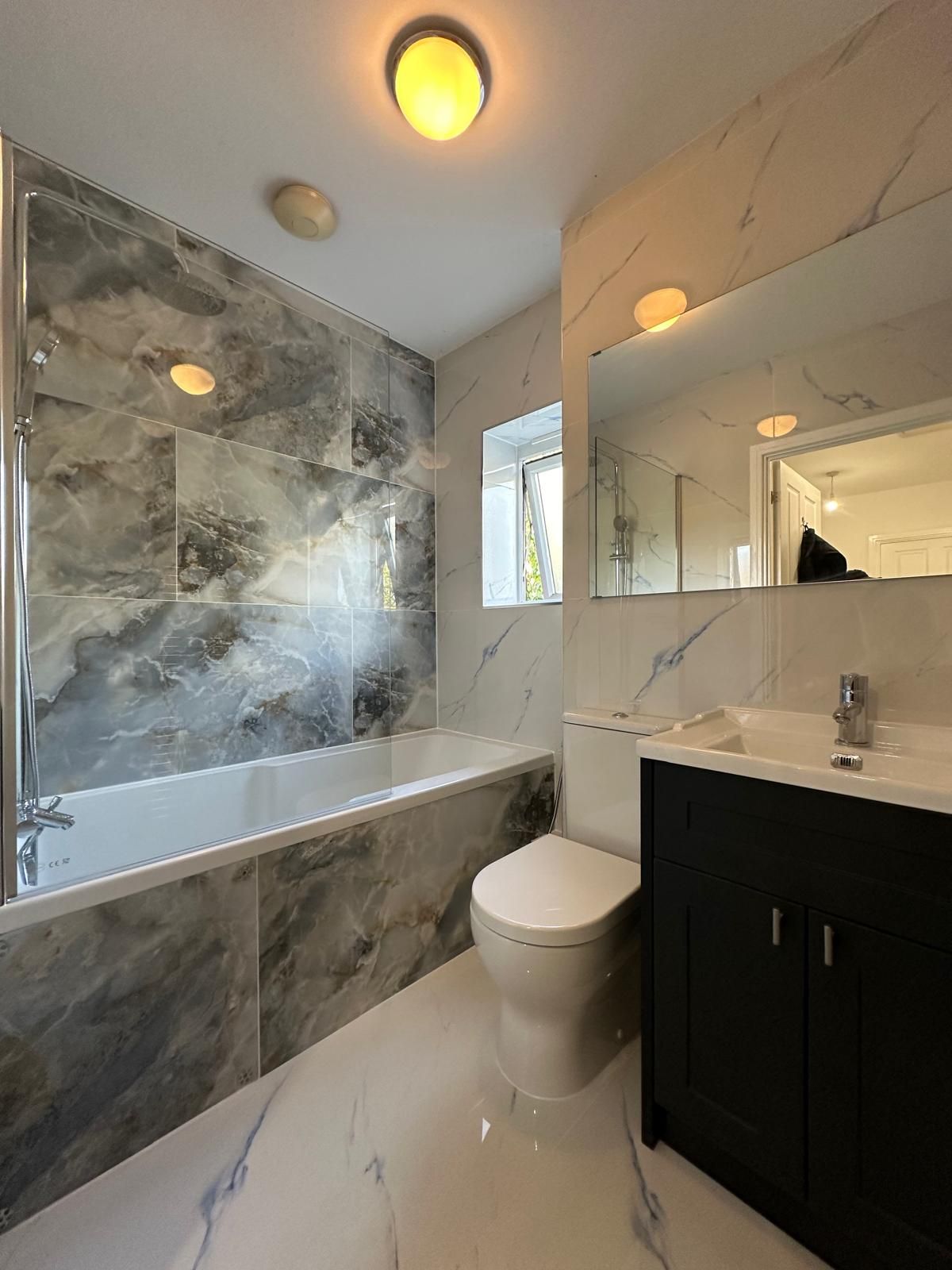 Freestanding bath with marble-effect tiling renovated by JFA Construction Group