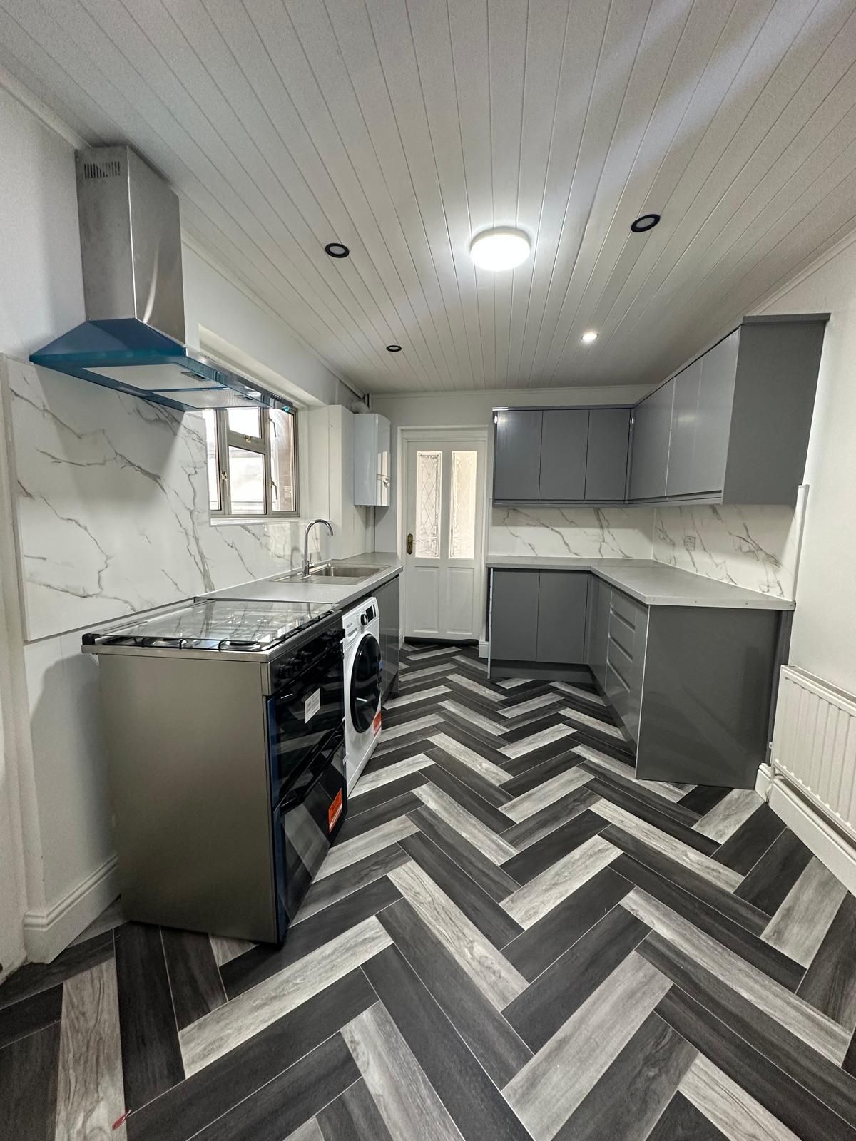 Grey kitchen with a herringbone-laid floor renovated by JFA Construction Group