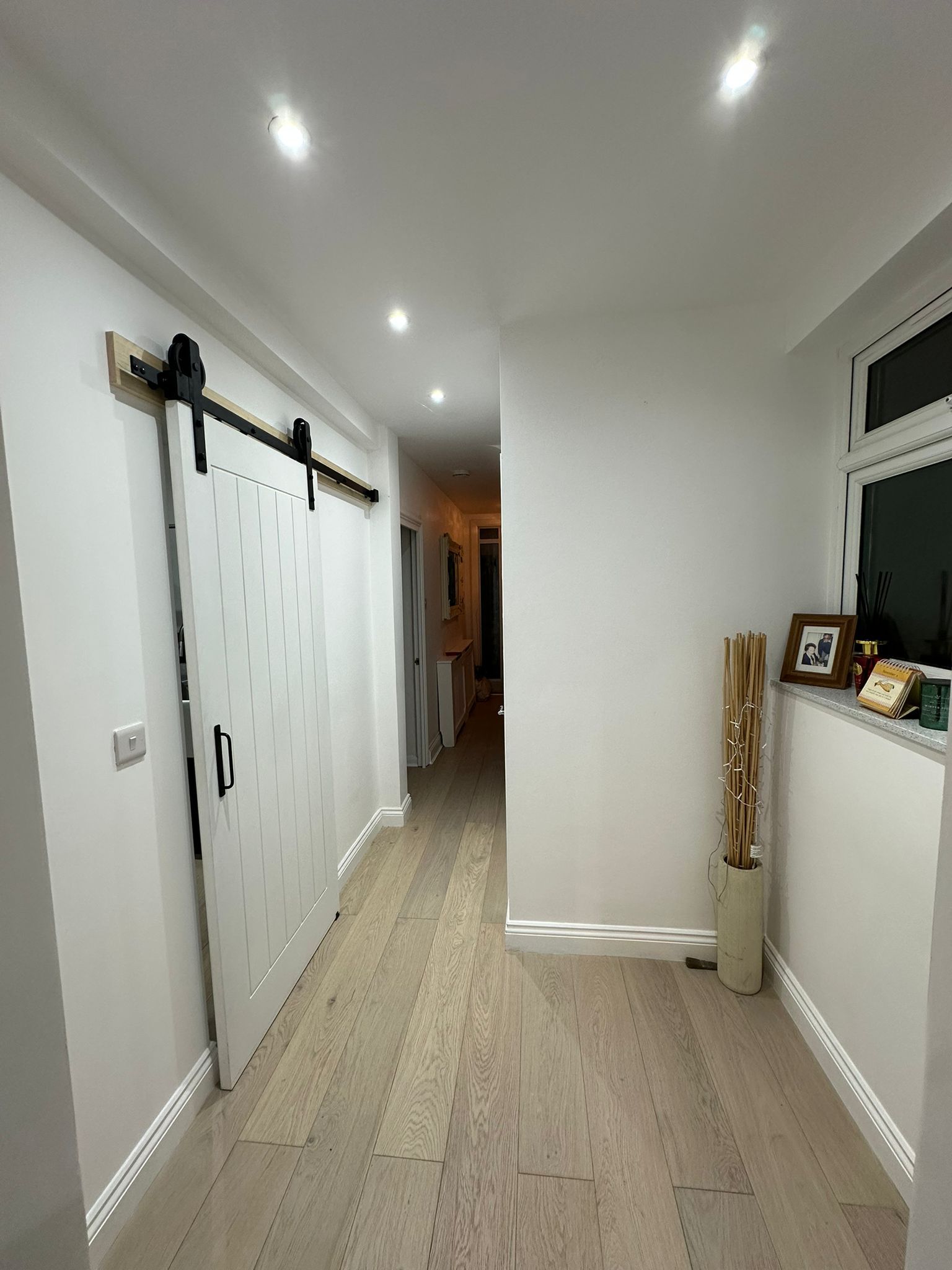 Renovated hallway with sliding barn door and herringbone flooring by JFA Construction Group
